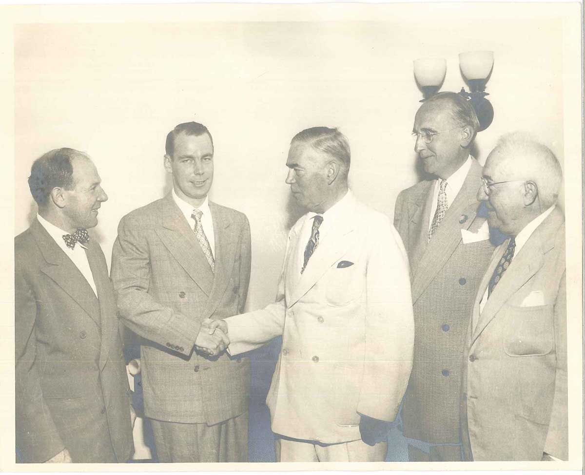 Kenneth Wynne shaking hands with his son John F Wynne Sr. and court clerk judges.